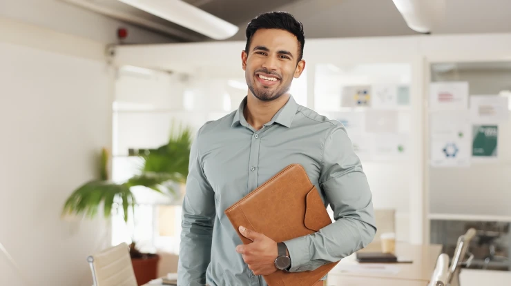 Dirigeant d’entreprise souriant dans un bureau moderne, tenant un dossier, représentant la réussite grâce à un ERP modulaire performant.